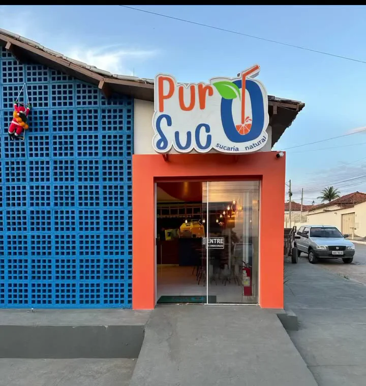 Fachada da Puro Suco Posse com entrada em laranja e parede azul